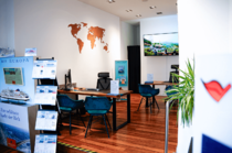 Moderner Innenbereich eines Reisebüros mit Beratungstischen und Weltkarte an der Wand.